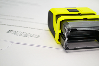 Image of a rubber stamp resting on a document, symbolizing an approved surety bond.